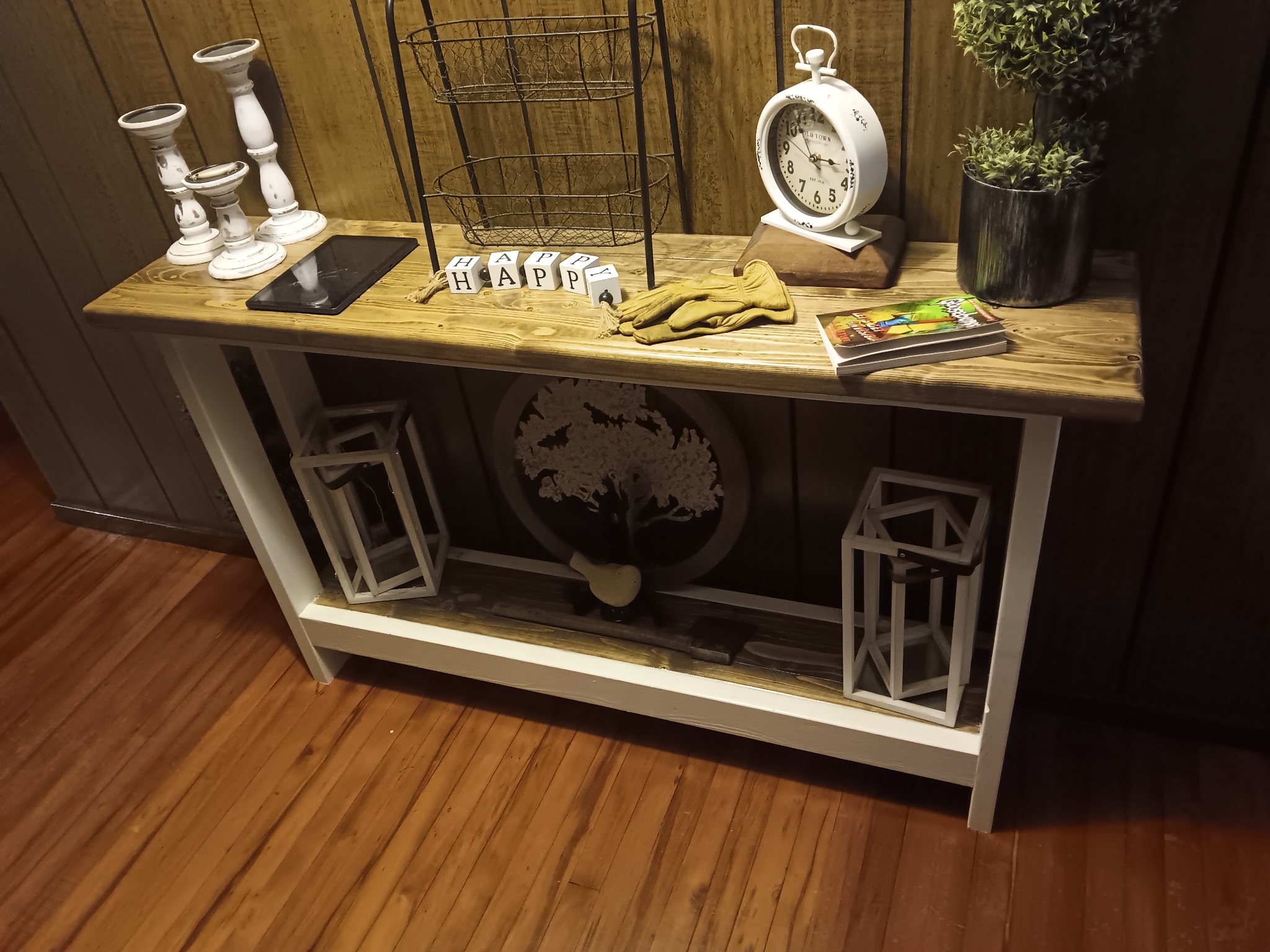 Finished farmhouse-style console table with stained pine top and white-finished base, styled on a hardwood floor.