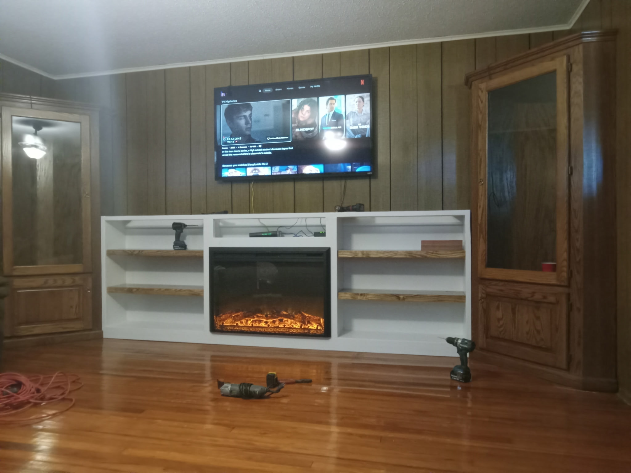 Finished living-room built-in with white-finished mantle, fireplace insert, and floating stained-pine shelves.
